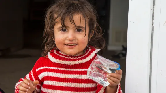 Die zweijährige Samira freut sich über sauberes Wasser. Sie hat mit ihrer Familie in einem Flüchtlingscamp nahe Dohuk Zuflucht gesucht. Foto: LWB/S. Salim