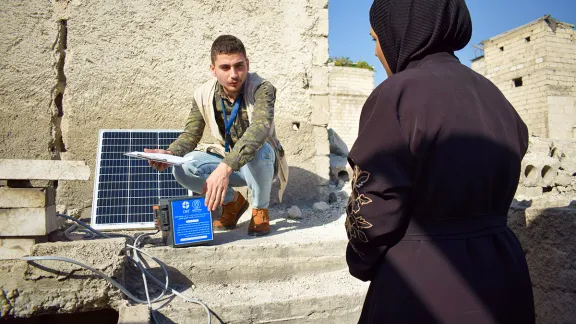 Ein LWB-Mitarbeiter zeigt Om Mohammad, wie das Solarpaneel aufgestellt wird. Foto: LWB Syrien