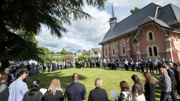 Die Gottesdienstbesucherinnen und -besucher versammeln sich im Rahmen des Eröffnungsgottesdienstes zur LWB-Ratstagung vor der Kirche Saint Robert in Founex zum Abendmahl. Foto: LWB/Albin Hillert