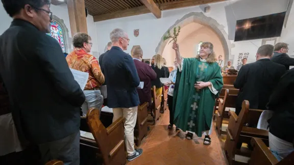 Tauferinnerung: Pfarrerin Katherine Gohm von der Evangelisch-Lutherischen Kirche in Kanada, die den Sonntagsgottesdienst in der Kirche La Dôle im schweizerischen Gingins leitete, besprengt die Gottesdienstteilnehmenden mit Wasser. Foto: LWB/Albin Hillert