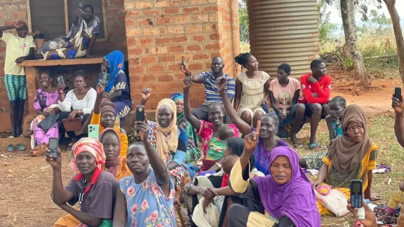 In der Flüchtlingssiedlung Kiryandongo zeigen Menschen die Mobiltelefone, die sie mithilfe einer einmaligen Beihilfe zur Registrierung gekauft haben, um den digitalen Zugang zu Bargeldhilfen zu ermöglichen. Foto: LWB Uganda