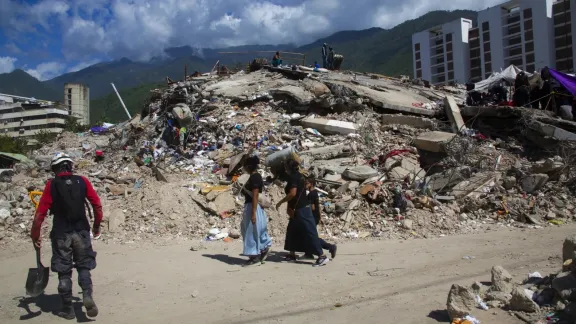 Menschen gehen durch ein Gebiet mit zerstörten Gebäuden in Tanaguarena, La Guaira. Foto: LWB/ Freisy González