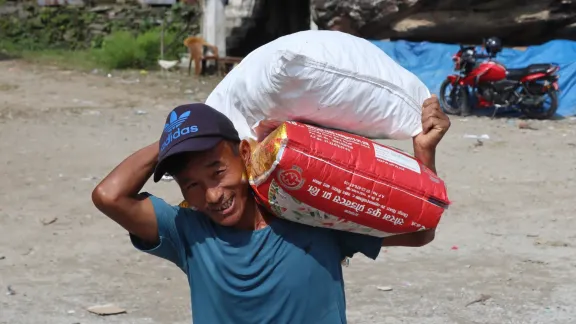 LWB Nepal verteilt weiterhin Hilfsgüter an überschwemmungsbetroffene Gemeinden im nördlichen Distrikt Rasuwa. Ein Mann trägt Lebensmittel zu seinem Zuhause in Uttargaya, Rasuwa. Foto: LWB Nepal